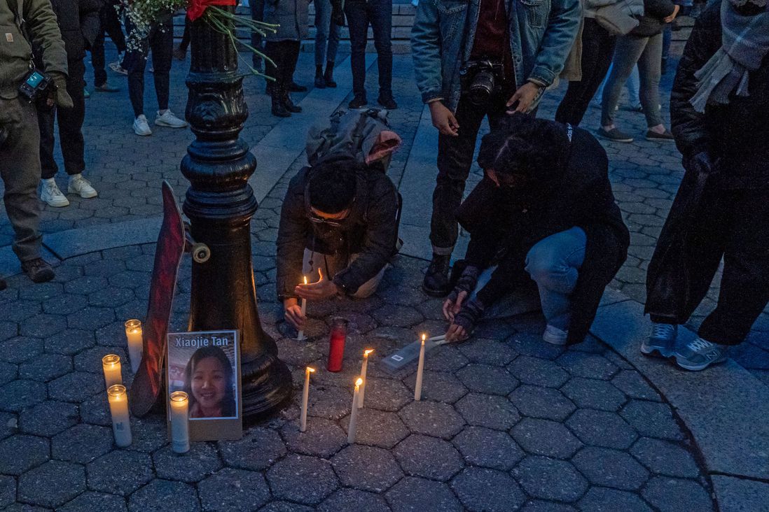 People bend down to light candles for the victims of the shootings